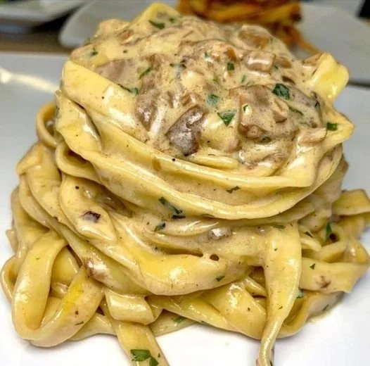 Tagliatelle servite con crema di parmigiano e funghi porcini in un piatto gourmet
